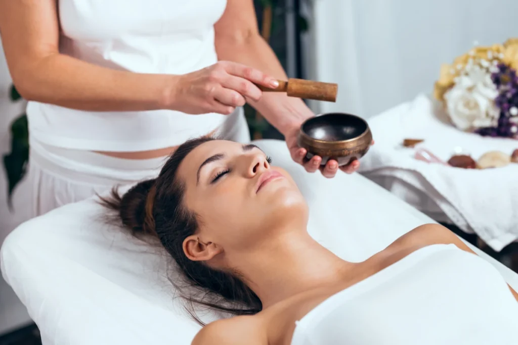 Thérapeute professionnel pratiquant le Reiki avec un bol chantant pour une session de guérison énergétique